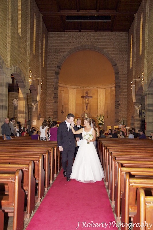 Groom kissing brides hand as they walk down the aisle at St Mary's North Sydney - wedding photography sydney